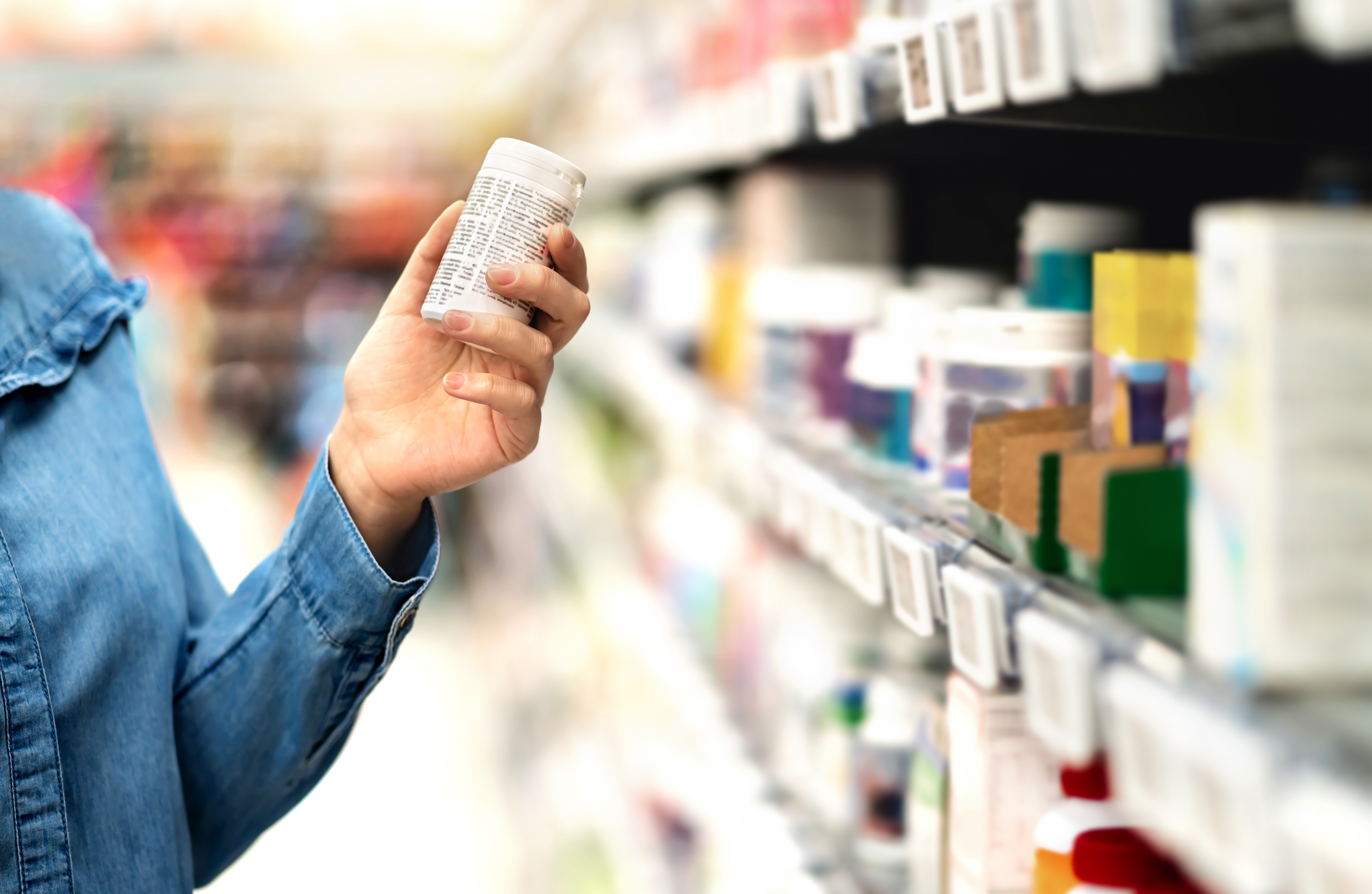 Customer in pharmacy holding medicine bottle